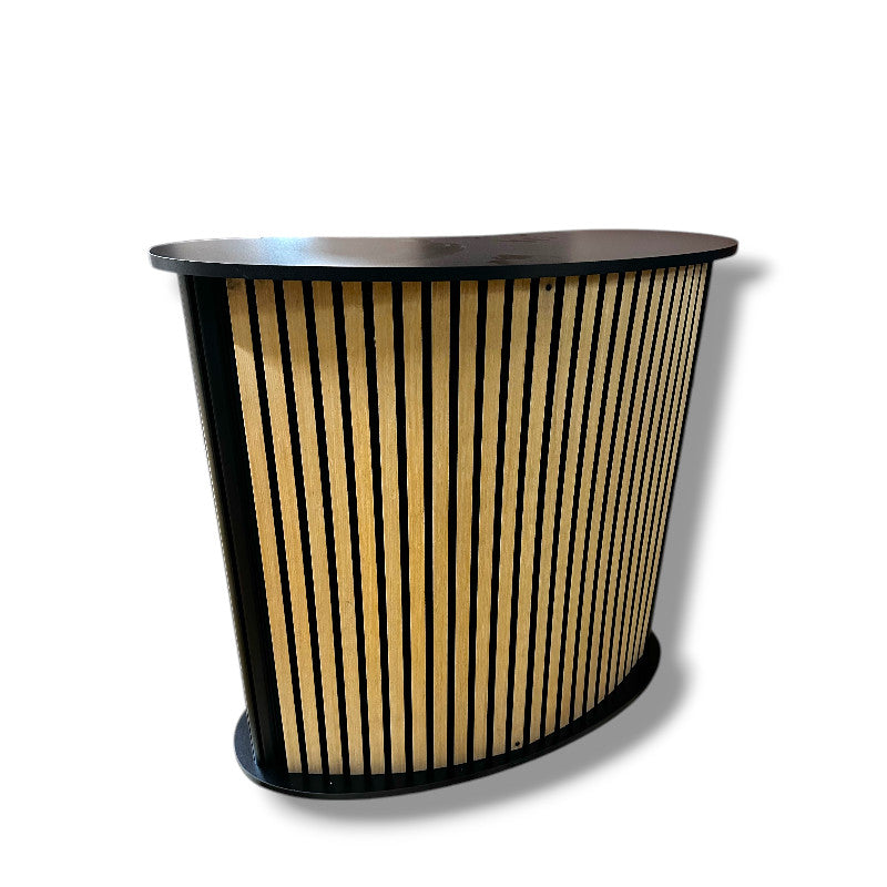 Kaareva levy hyllyllä. Etupuoli akustikkolevyllä / puulameleilla. L104 x S43 x K105 cm.