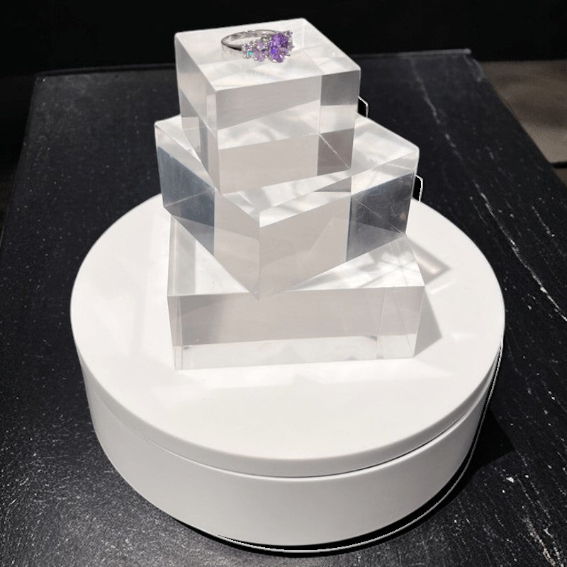 SuperSellerS white electronic rotating display stand with clear acrylic blocks showcasing a purple gemstone ring